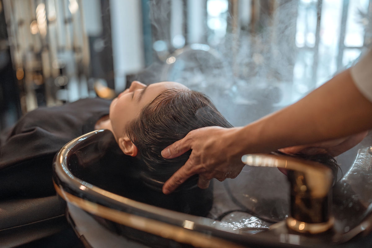 Stylist carefully cleansing a client's hair at the shampoo bowl